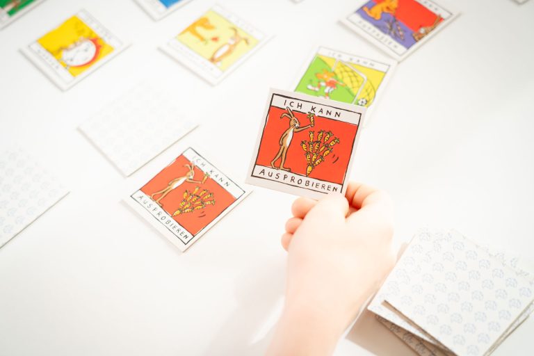 Kind hält eine Memory-Karte mit der Aufschrift „Ich kann ausprobieren“ in der Praxis für Kinder- und Jugendpsychiatrie von Andrea Fleßner-Polychronidis in Hannover-Kirchrode. Die Karten regen zum Gespräch über Gefühle, Fähigkeiten und Alltagsbewältigung an.